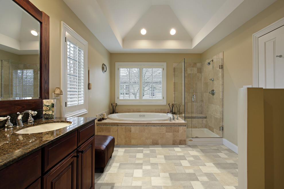 Стильный дизайн: большая главная ванная комната в классическом стиле с фасадами с выступающей филенкой, темными деревянными фасадами, накладной ванной, угловым душем, раздельным унитазом, бежевой плиткой, коричневой плиткой, серой плиткой, цементной плиткой, бежевыми стенами, полом из цементной плитки, врезной раковиной, столешницей из гранита, бежевым полом и душем с распашными дверями - последний тренд