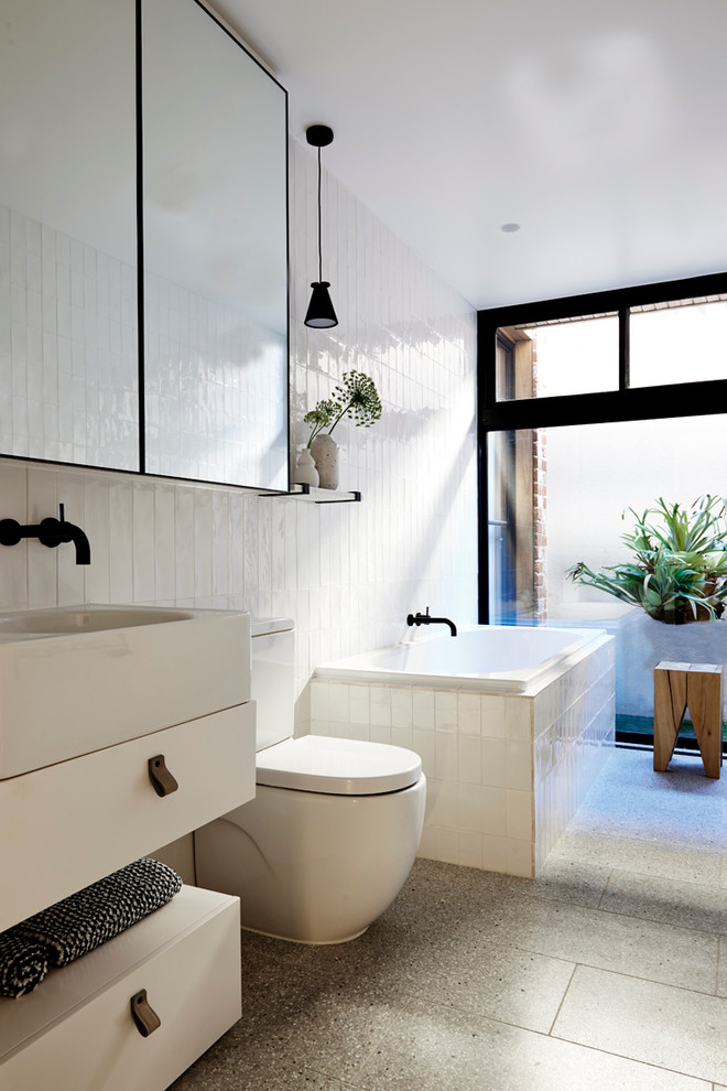 Mittelgroßes Modernes Badezimmer mit profilierten Schrankfronten, Eckbadewanne, Wandtoilette mit Spülkasten, weißen Fliesen, Porzellanfliesen, weißer Wandfarbe, Keramikboden und Mineralwerkstoff-Waschtisch in Melbourne