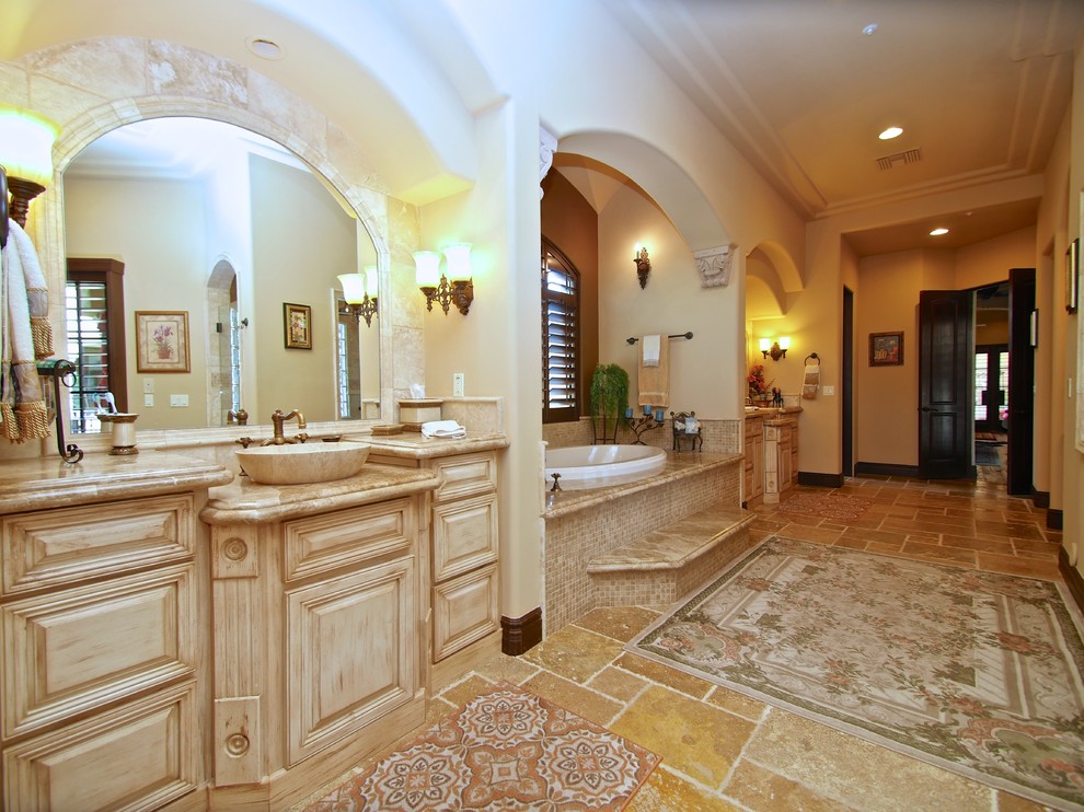 Inspiration for a large mediterranean master black tile and stone tile travertine floor bathroom remodel in Phoenix with recessed-panel cabinets, light wood cabinets, a two-piece toilet, beige walls, a wall-mount sink and granite countertops