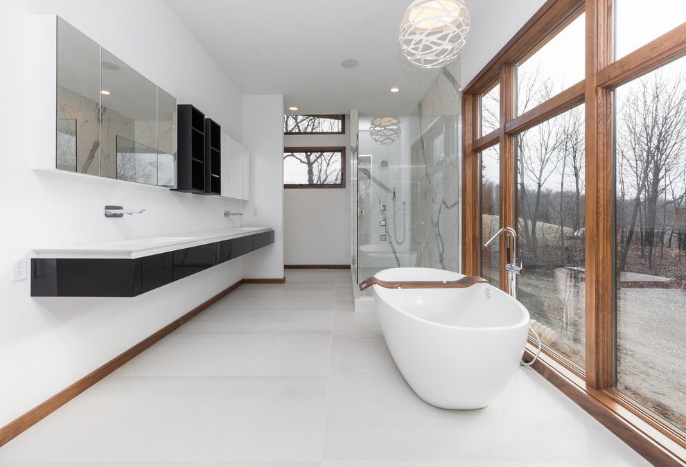Modernes Badezimmer mit freistehender Badewanne, Eckdusche, grauen Fliesen und integriertem Waschbecken in Sonstige