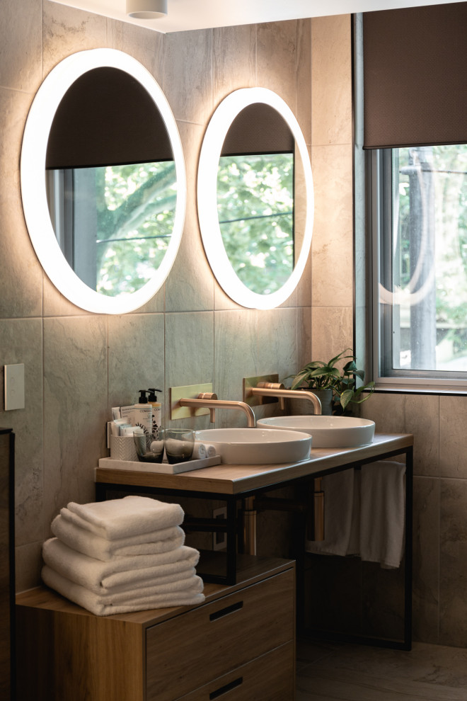 Ispirazione per una stanza da bagno design con piastrelle grigie, lavabo a bacinella, top in legno e due lavabi