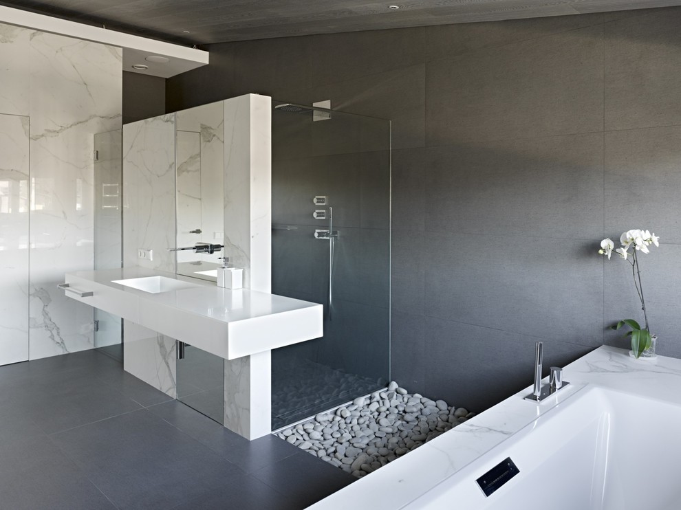 Idee per un'ampia stanza da bagno padronale minimal con ante bianche, doccia alcova, lastra di pietra, pareti bianche, lavabo integrato e vasca da incasso
