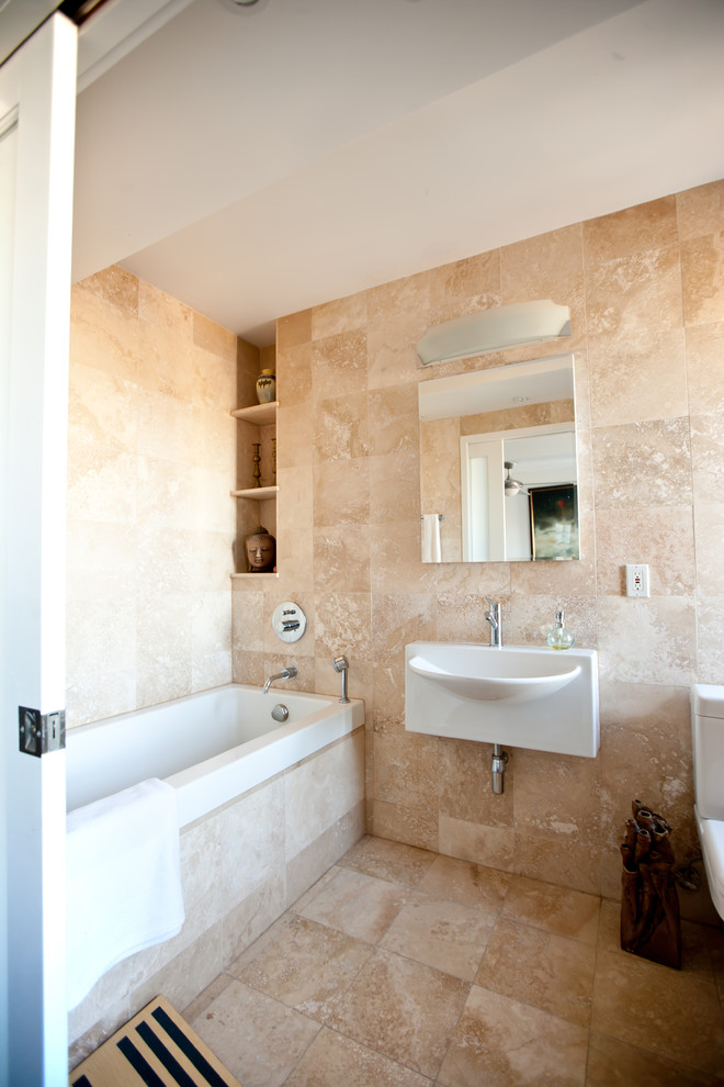 На фото: ванная комната в классическом стиле с подвесной раковиной и плиткой из травертина с