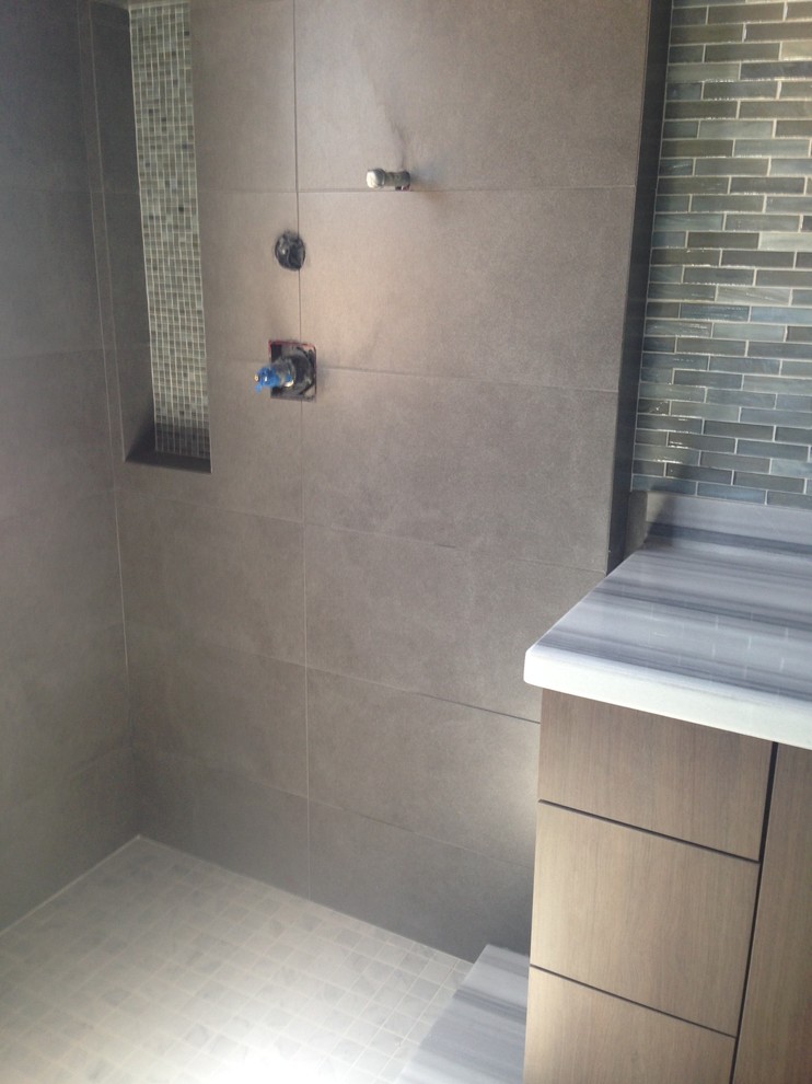 Bild på ett stort funkis badrum, med ett undermonterad handfat, marmorbänkskiva, ett fristående badkar, en toalettstol med hel cisternkåpa, grå kakel, porslinskakel, blå väggar och klinkergolv i porslin