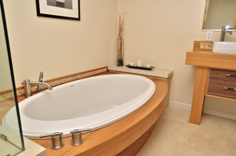 This is an example of a large contemporary ensuite bathroom in San Francisco with a vessel sink, light wood cabinets, wooden worktops, a one-piece toilet, beige tiles, stone tiles, beige walls and travertine flooring.