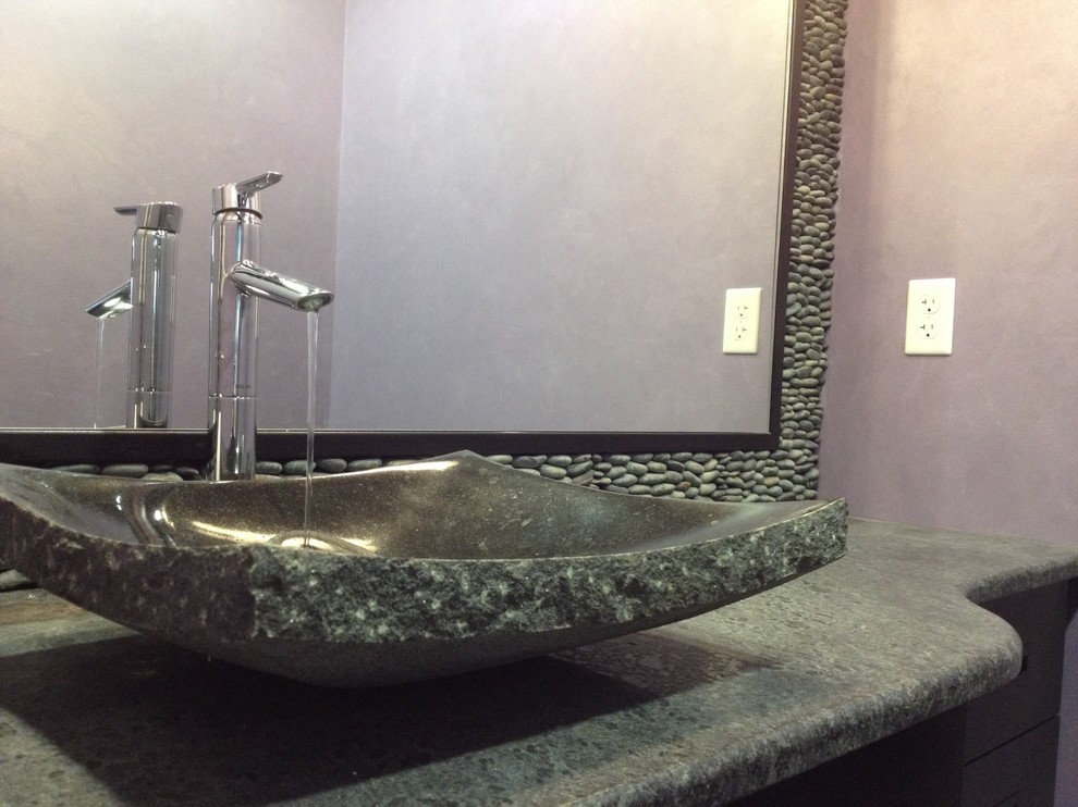 Ispirazione per una stanza da bagno etnica con lavabo a bacinella, consolle stile comò, ante nere, top in granito, piastrelle nere e piastrelle in pietra