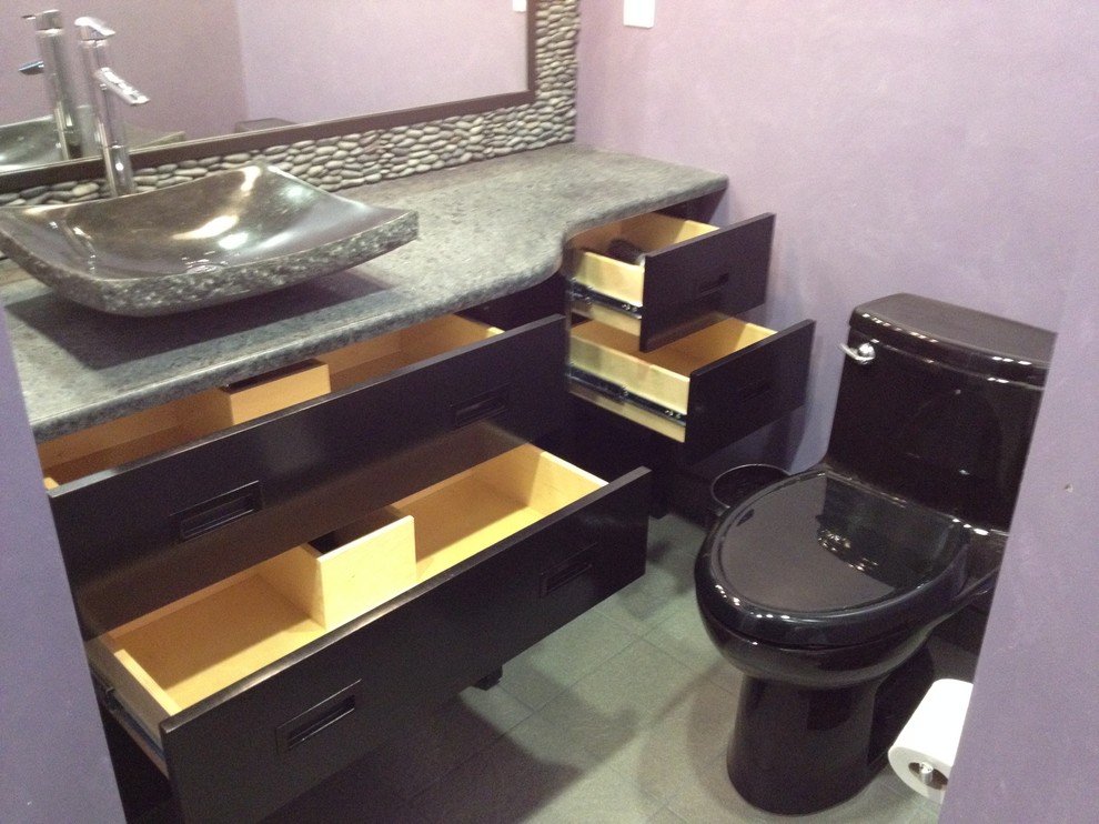 Esempio di una stanza da bagno etnica con lavabo a bacinella, consolle stile comò, ante nere, top in granito, piastrelle nere e piastrelle in pietra