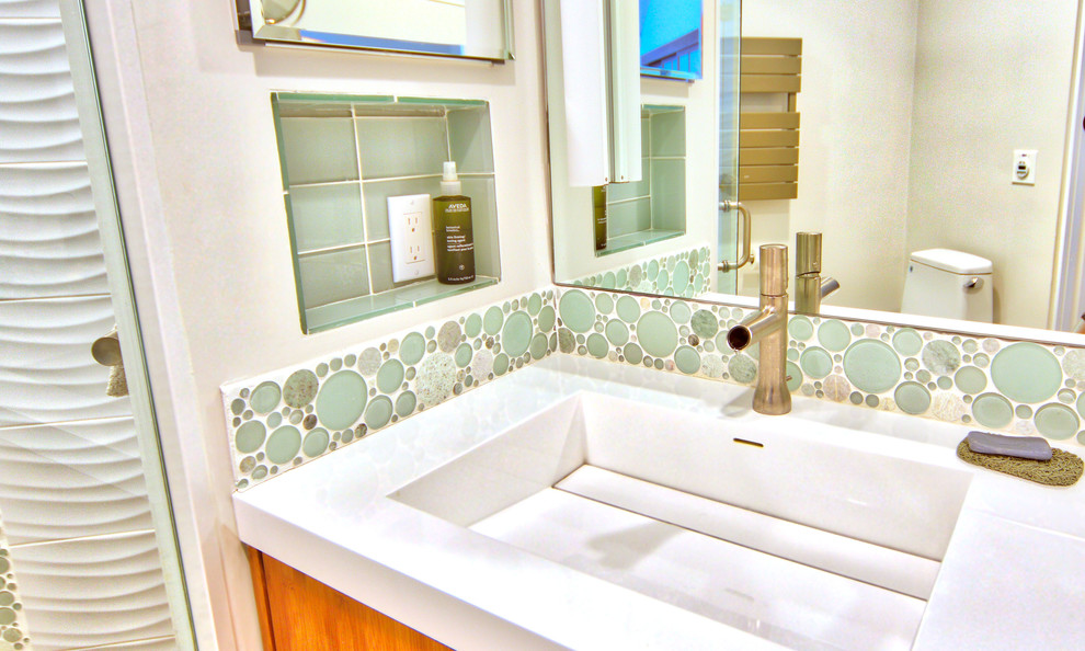 Modernes Duschbad mit flächenbündigen Schrankfronten, hellbraunen Holzschränken, Duschnische, Keramikfliesen, weißer Wandfarbe, integriertem Waschbecken, Mineralwerkstoff-Waschtisch, Falttür-Duschabtrennung und weißer Waschtischplatte