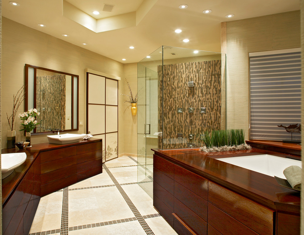 This is an example of a large world-inspired ensuite bathroom in Dallas with a built-in shower, travertine flooring, wooden worktops, flat-panel cabinets, dark wood cabinets, a vessel sink, beige walls, a submerged bath, matchstick tiles, beige floors and a hinged door.