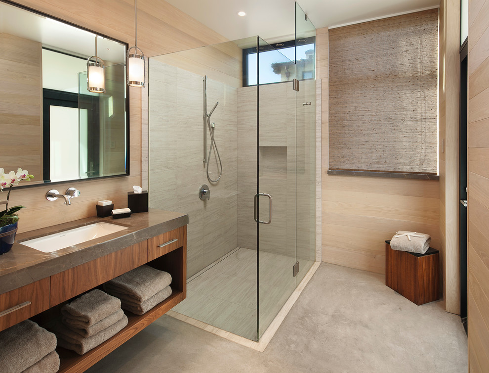Cette image montre une salle d'eau design en bois brun avec une douche d'angle, un carrelage beige, un carrelage de pierre, un lavabo encastré et un placard sans porte.