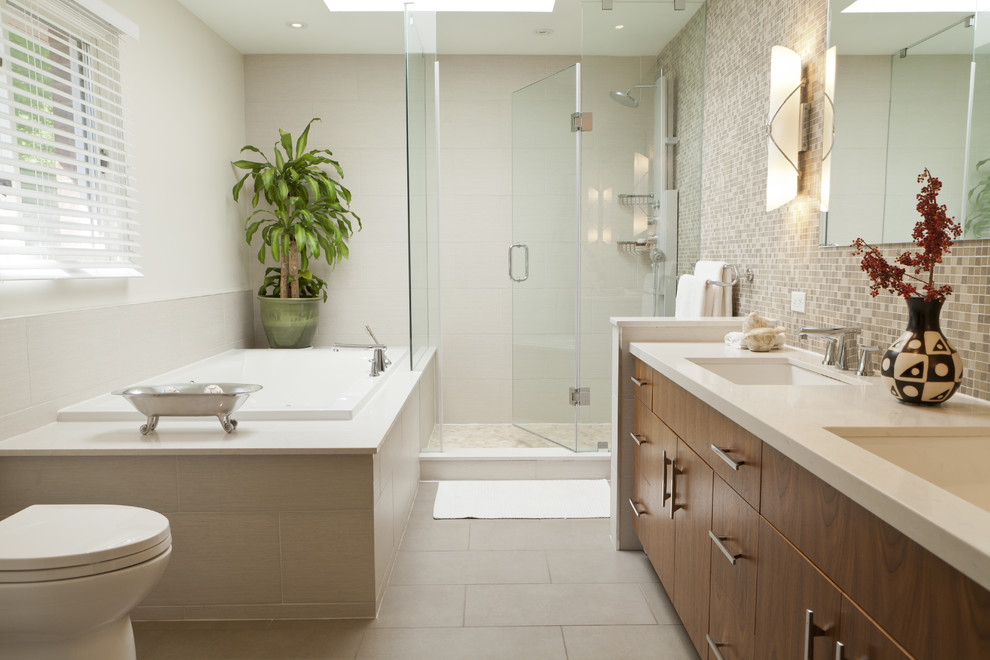Modern inredning av ett badrum, med ett undermonterad handfat, släta luckor, skåp i mellenmörkt trä, bänkskiva i kvarts, ett platsbyggt badkar, en dusch i en alkov, beige kakel och mosaik
