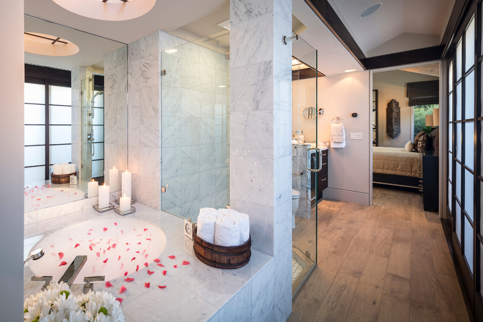 Cette photo montre une salle de bain principale tendance en bois foncé de taille moyenne avec un lavabo encastré, un placard à porte plane, un plan de toilette en marbre, un bain japonais, une douche ouverte, un bidet, un carrelage blanc, des dalles de pierre, un mur beige et un sol en carrelage de porcelaine.