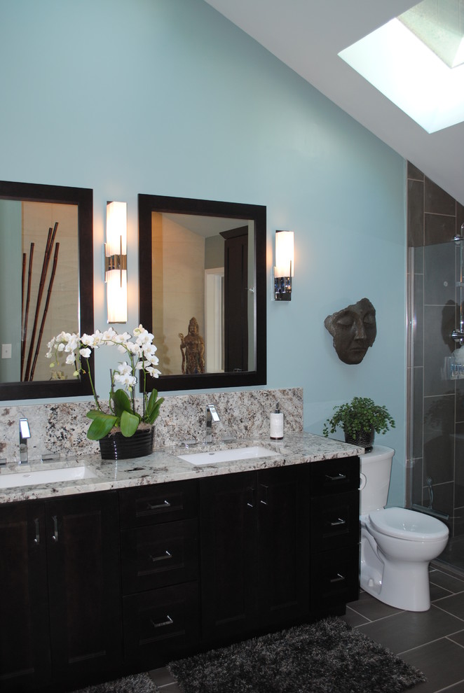 Exemple d'une grande salle de bain principale asiatique en bois foncé avec un lavabo encastré, un placard à porte shaker, un plan de toilette en granite, une baignoire indépendante, WC séparés et un mur bleu.