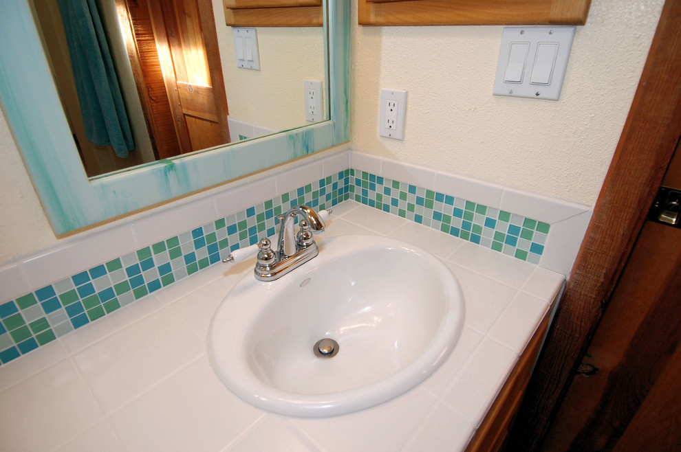 Mittelgroßes Maritimes Duschbad mit Toilette mit Aufsatzspülkasten, Einbauwaschbecken, Schrankfronten mit vertiefter Füllung, hellbraunen Holzschränken, blauen Fliesen, weißer Wandfarbe und gefliestem Waschtisch in Portland