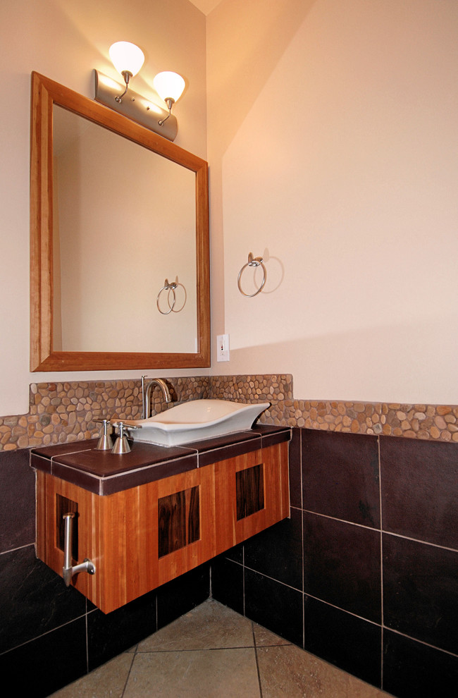 Immagine di una stanza da bagno con doccia etnica di medie dimensioni con lavabo a bacinella, ante lisce, ante in legno scuro, piastrelle marroni e pareti bianche