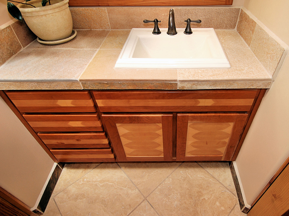 Mid-sized arts and crafts 3/4 brown tile bathroom photo in Portland with medium tone wood cabinets, recessed-panel cabinets, a one-piece toilet, beige walls and a drop-in sink