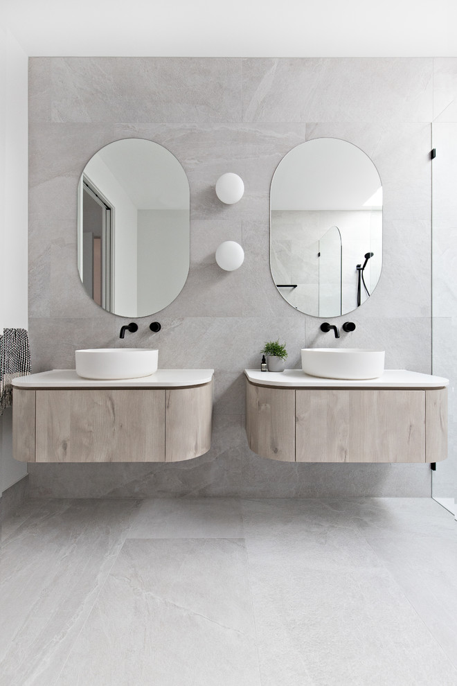 Réalisation d'une salle de bain minimaliste en bois clair avec un placard à porte plane, un carrelage beige, un mur blanc, une vasque, un sol beige et un plan de toilette blanc.