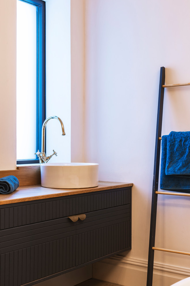 マンチェスターにあるトランジショナルスタイルのおしゃれな浴室 (青いキャビネット、白い壁、大理石の床、木製洗面台) の写真