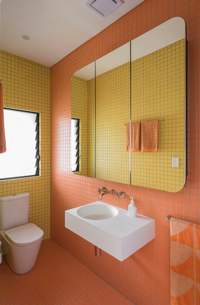 Идея дизайна: маленькая главная ванная комната в современном стиле с подвесной раковиной, плоскими фасадами, черными фасадами, столешницей из искусственного камня, душем в нише, унитазом-моноблоком, желтой плиткой, оранжевой плиткой, керамической плиткой, оранжевыми стенами и полом из керамической плитки для на участке и в саду