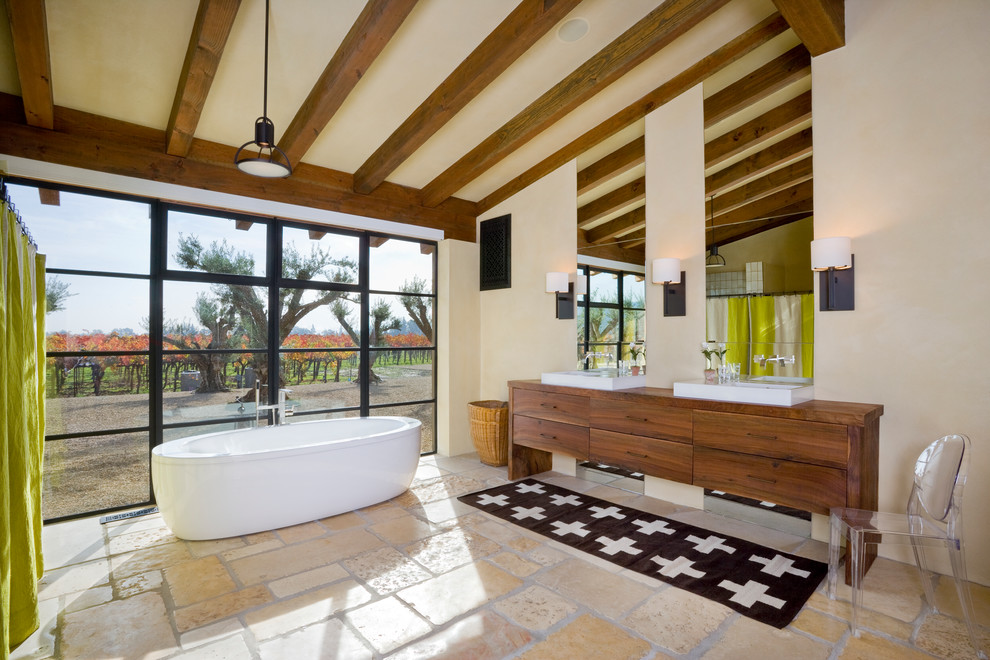 Réalisation d'une salle de bain méditerranéenne en bois brun avec un placard à porte plane, un plan de toilette en bois, une baignoire indépendante et un mur beige.