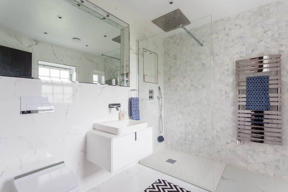 ハートフォードシャーにある中くらいなコンテンポラリースタイルのおしゃれな浴室 (フラットパネル扉のキャビネット、白いキャビネット、白い床、壁掛け式トイレ、白いタイル、大理石タイル、白い壁、大理石の床、ベッセル式洗面器、オープンシャワー、白い洗面カウンター) の写真