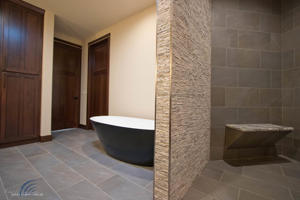 Photo of a large traditional ensuite bathroom in Other with a freestanding bath, a built-in shower, beige tiles, stone tiles, beige walls, porcelain flooring, beige floors and a shower bench.