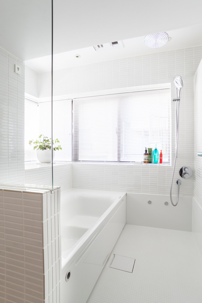 東京23区にある小さなモダンスタイルのおしゃれなマスターバスルーム (アルコーブ型浴槽、シャワー付き浴槽	、白いタイル、ボーダータイル、白い壁、セラミックタイルの床) の写真