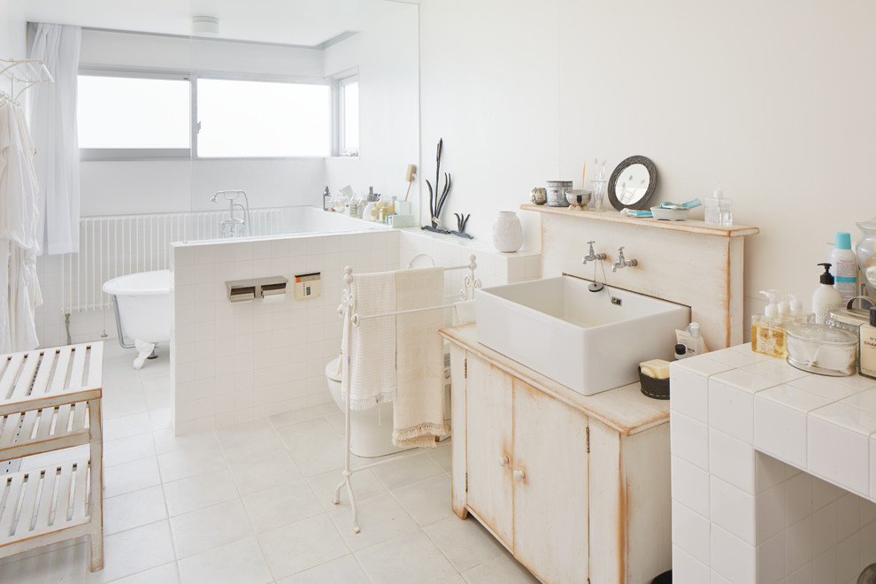 Exemple d'une salle de bain éclectique avec des portes de placard beiges, une baignoire sur pieds, un combiné douche/baignoire, un mur blanc, une vasque, un plan de toilette en bois et un placard à porte plane.