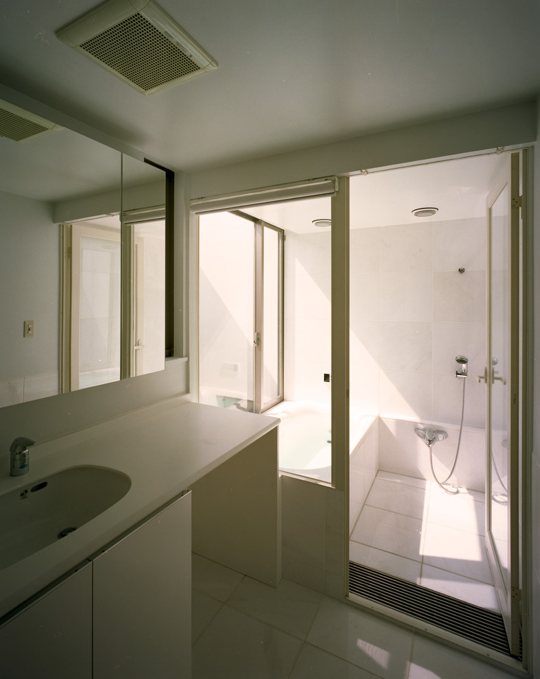 Idée de décoration pour une salle de bain principale minimaliste de taille moyenne avec un placard à porte affleurante, des portes de placard blanches, une baignoire posée, un combiné douche/baignoire, WC à poser, un carrelage blanc, du carrelage en marbre, un mur blanc, un sol en marbre, un lavabo encastré, un plan de toilette en surface solide, un sol blanc, une cabine de douche à porte battante et un plan de toilette blanc.