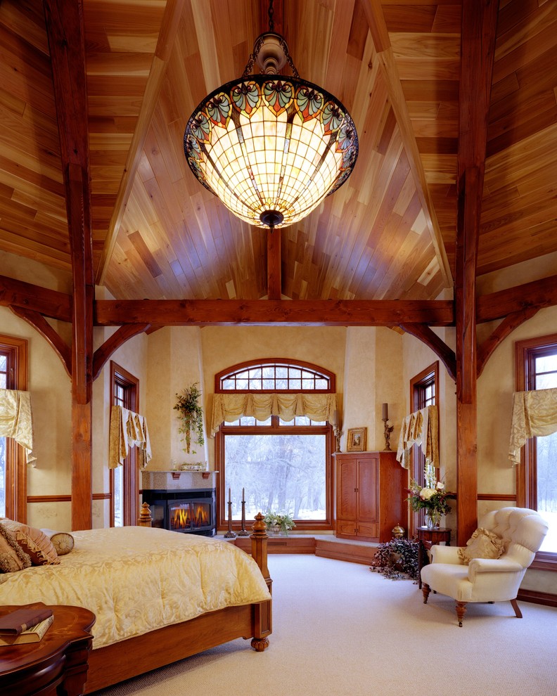 他の地域にある広いトラディショナルスタイルのおしゃれな主寝室 (黄色い壁、カーペット敷き、コーナー設置型暖炉、石材の暖炉まわり) のインテリア