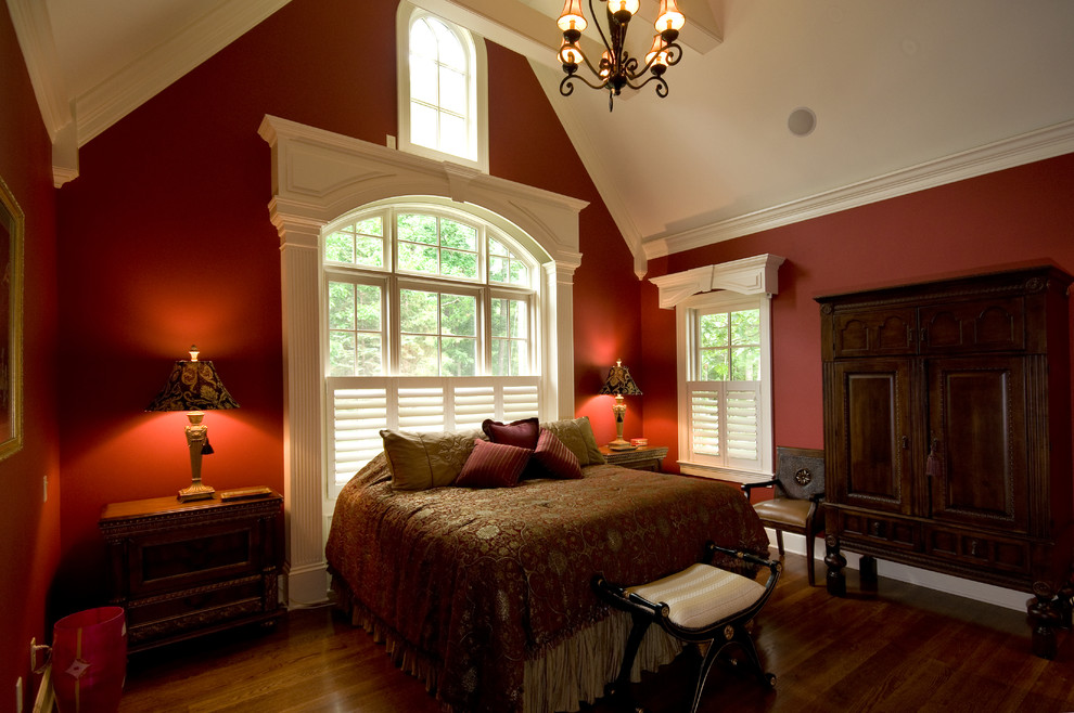 Aménagement d'une grande chambre parentale classique avec un mur rouge, parquet foncé, aucune cheminée et un sol marron.