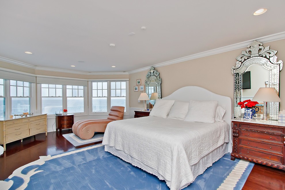 Geräumiges Maritimes Hauptschlafzimmer mit beiger Wandfarbe und dunklem Holzboden in New York