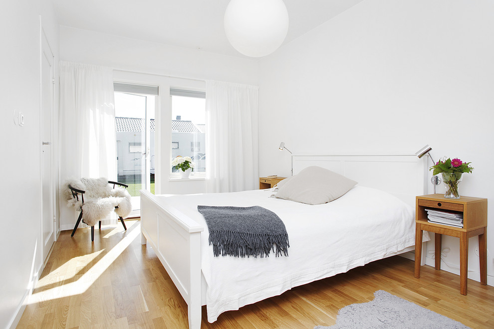 Example of a mid-sized trendy master light wood floor bedroom design in Other with white walls and no fireplace