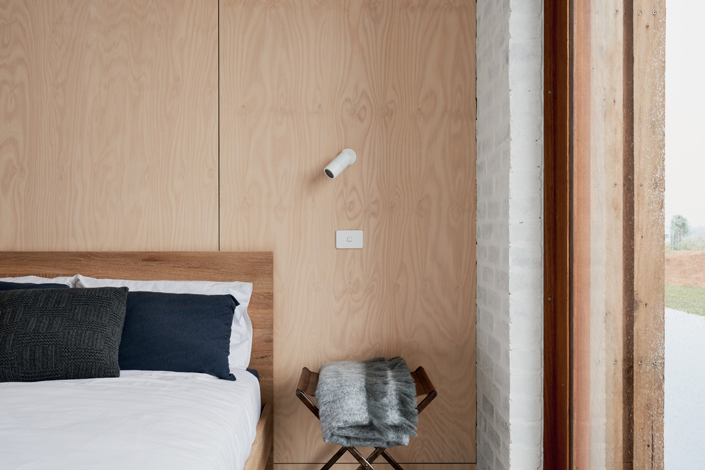 Cette image montre une chambre parentale design avec un mur beige, sol en béton ciré et un sol gris.