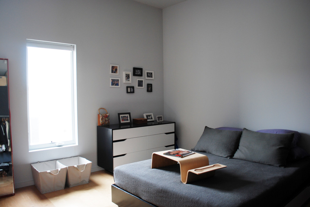 Foto di una camera da letto moderna con pareti grigie e pavimento in legno massello medio