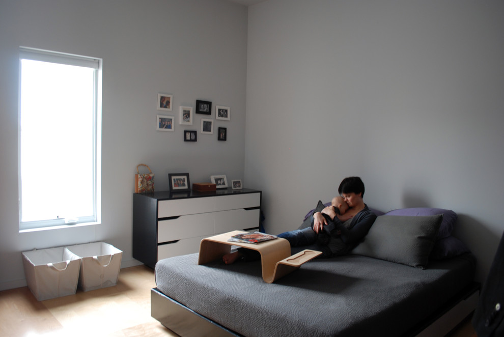 Ispirazione per una camera da letto moderna con pareti grigie e parquet chiaro