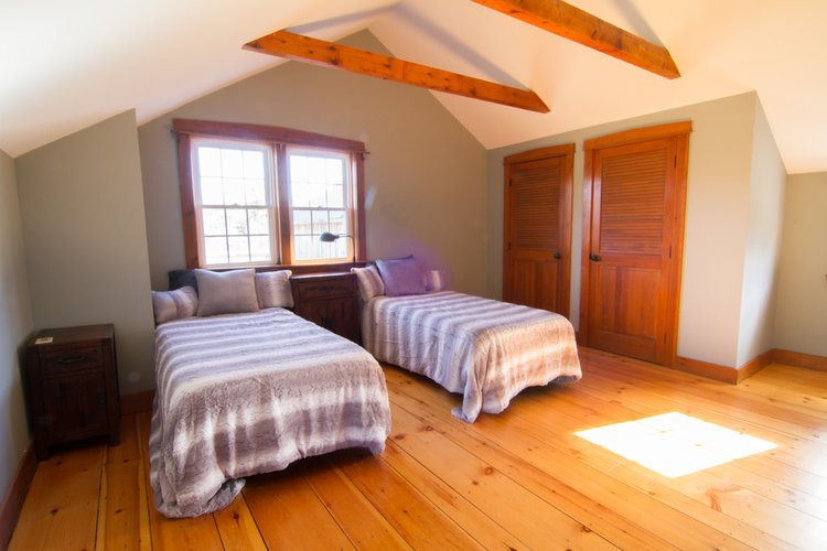 Diseño de dormitorio campestre con paredes verdes, suelo de madera clara y suelo marrón