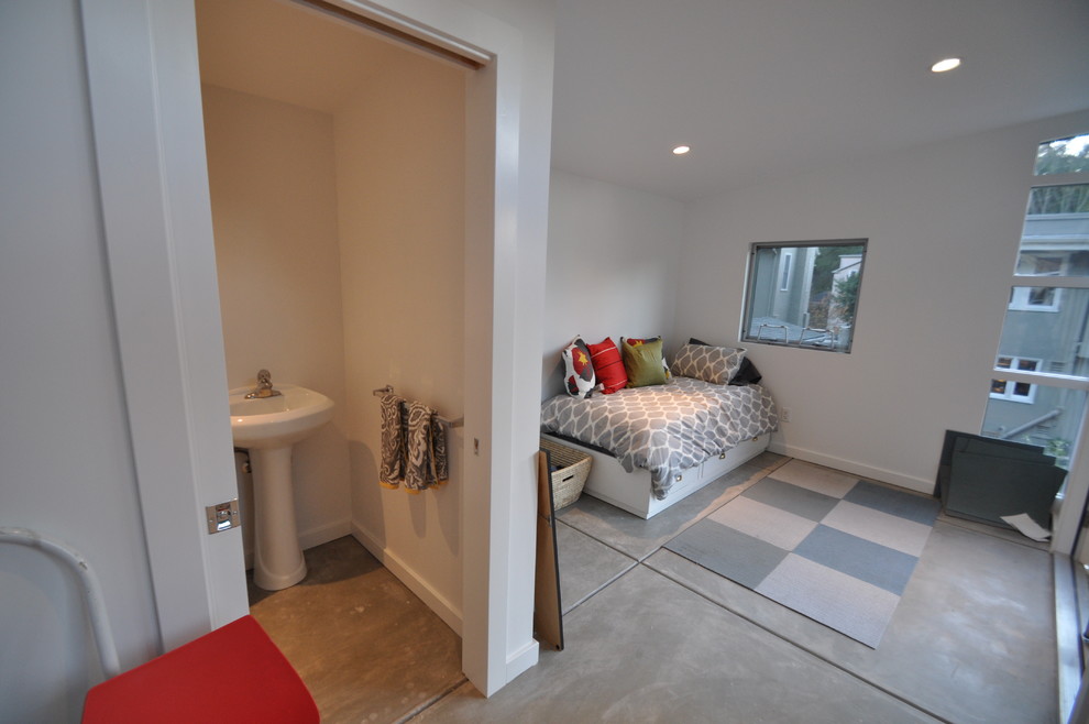 Idee per un'ampia camera degli ospiti minimalista con pareti bianche e pavimento in cemento