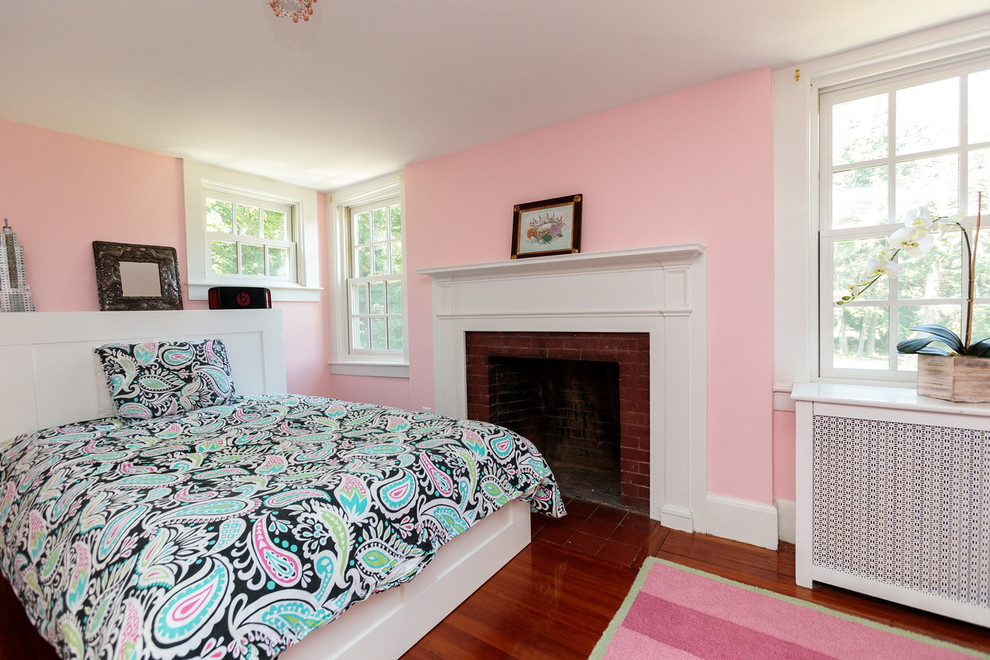 Exempel på ett mellanstort klassiskt gästrum, med rosa väggar, mellanmörkt trägolv, beiget golv, en standard öppen spis och en spiselkrans i trä