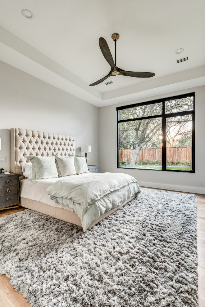 Modernes Hauptschlafzimmer mit weißer Wandfarbe, hellem Holzboden und braunem Boden in Dallas