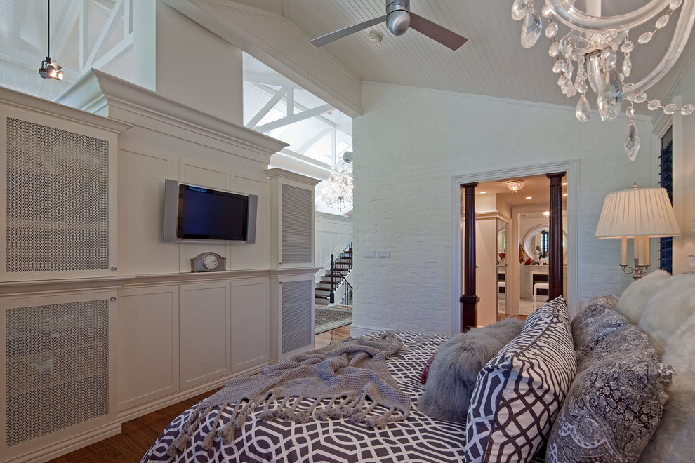 Ejemplo de dormitorio televisión actual con paredes blancas y suelo de madera en tonos medios