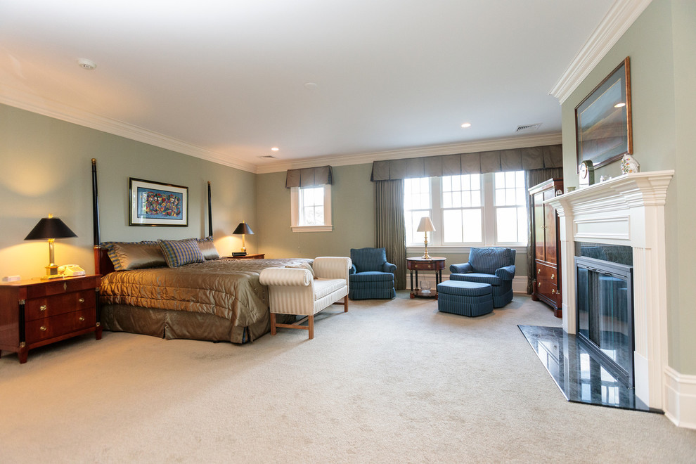 Geräumiges Klassisches Hauptschlafzimmer mit grüner Wandfarbe, braunem Holzboden, Kamin, Kaminumrandung aus Holz und grünem Boden in Boston