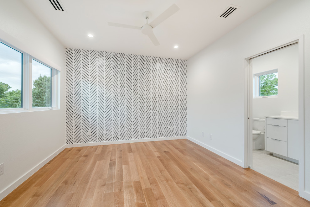 Diseño de habitación de invitados minimalista con paredes blancas, suelo de madera en tonos medios, suelo marrón y papel pintado