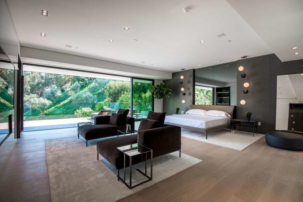 Contemporary master and grey and black bedroom in Los Angeles with black walls, medium hardwood flooring, a ribbon fireplace and beige floors.