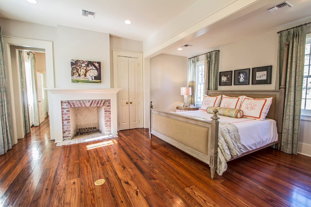 Inspiration for a large timeless master medium tone wood floor bedroom remodel in New Orleans with white walls, a standard fireplace and a brick fireplace