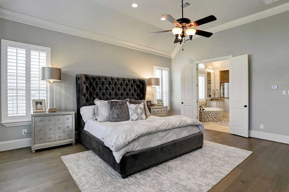 ヒューストンにある広いトランジショナルスタイルのおしゃれな主寝室 (グレーの壁、淡色無垢フローリング、茶色い床)