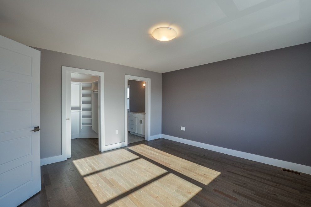 Ejemplo de dormitorio principal tradicional de tamaño medio con paredes grises, suelo de madera en tonos medios y suelo marrón
