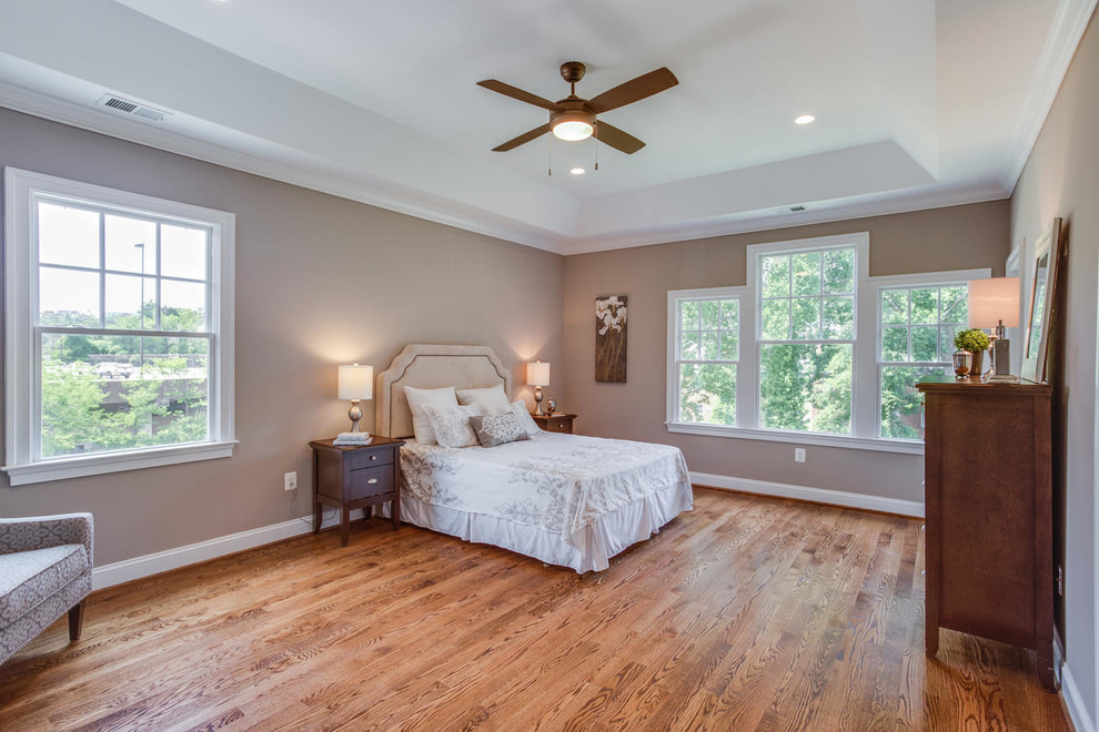 Aménagement d'une chambre parentale classique avec un mur beige, un sol en bois brun et aucune cheminée.