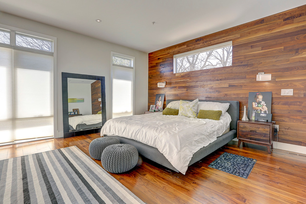 Cette image montre une chambre parentale design avec un mur multicolore, un sol en bois brun et aucune cheminée.