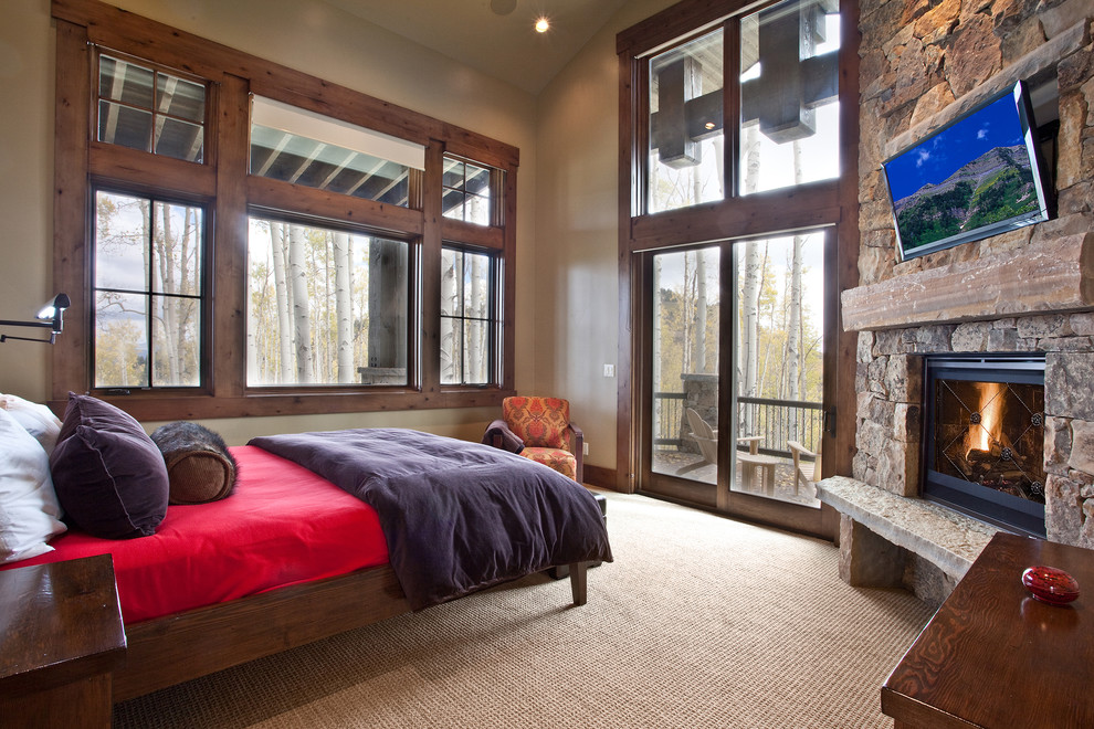 Exemple d'une chambre avec moquette montagne avec un mur beige, une cheminée d'angle et un manteau de cheminée en pierre.